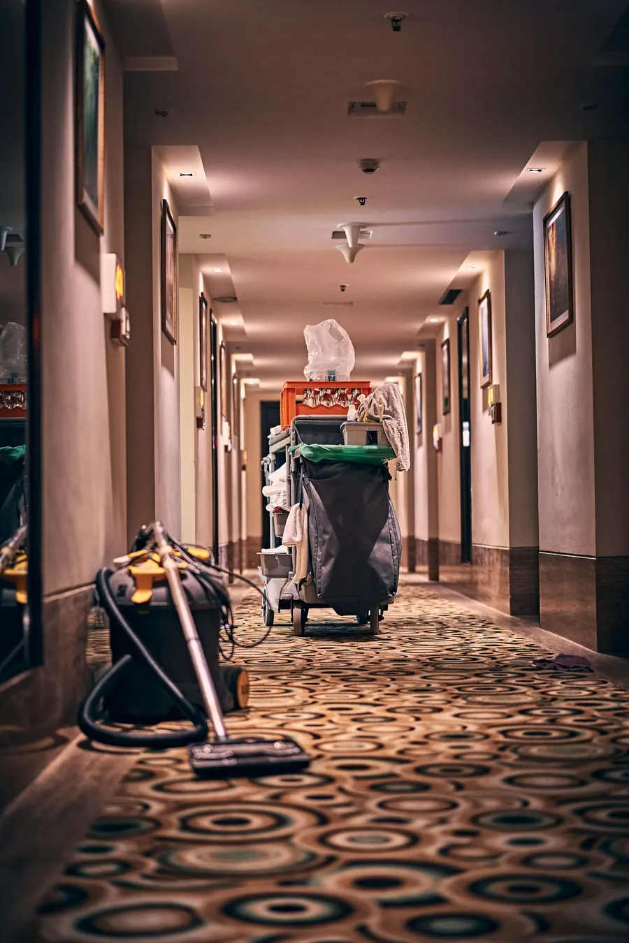 A Shining Services cleaner working through a hotel corridor after hours